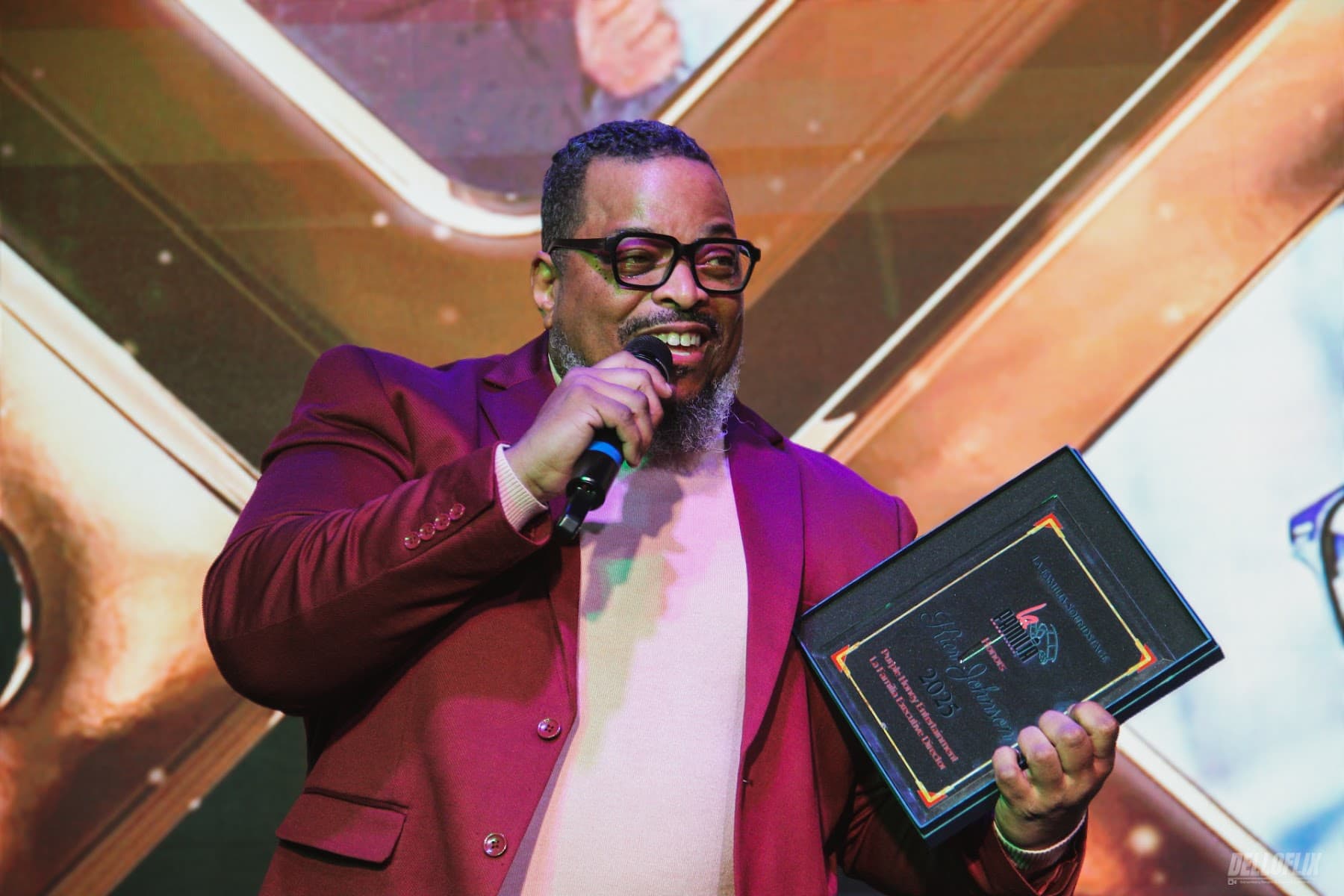 Event photography of an honoree speaking with his award at La Familia Soundstage