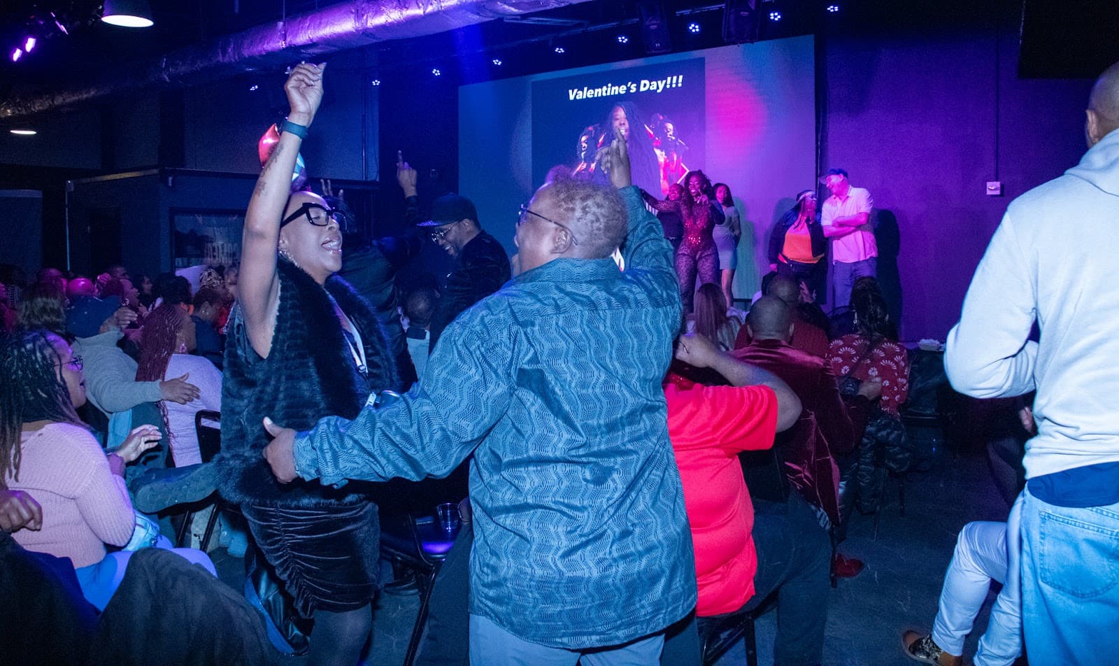 A packed crowd laughing and cheering at a comedy show