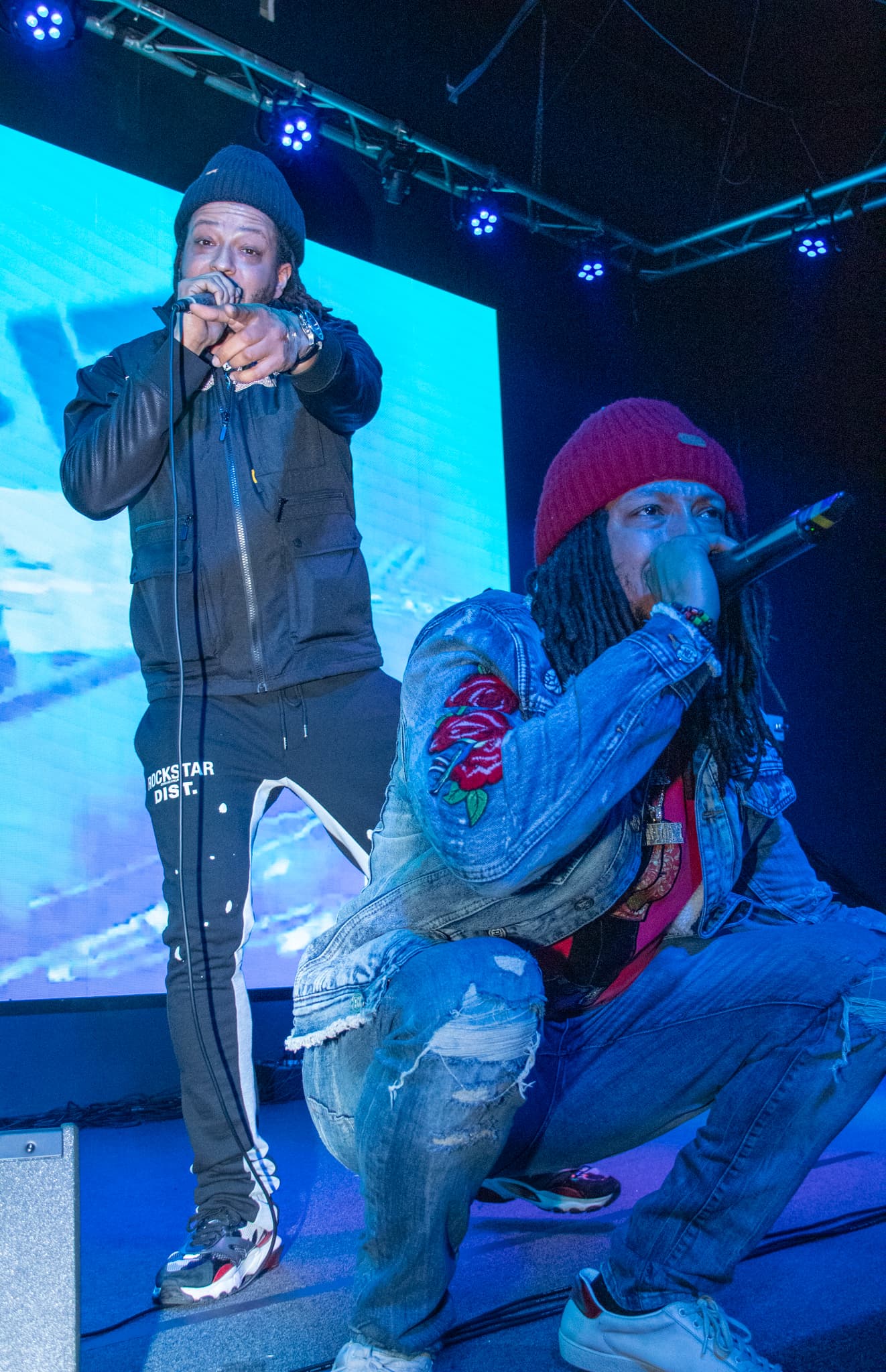 Two hip-hop artists performing under blue stage light