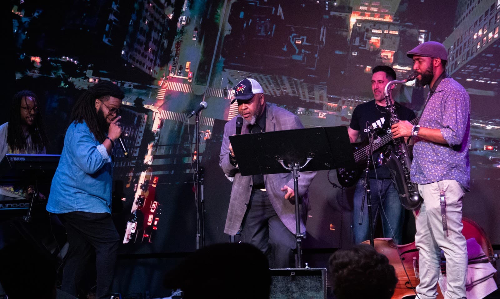 A jazz quartet performing in front of a glowing city skyline backdrop