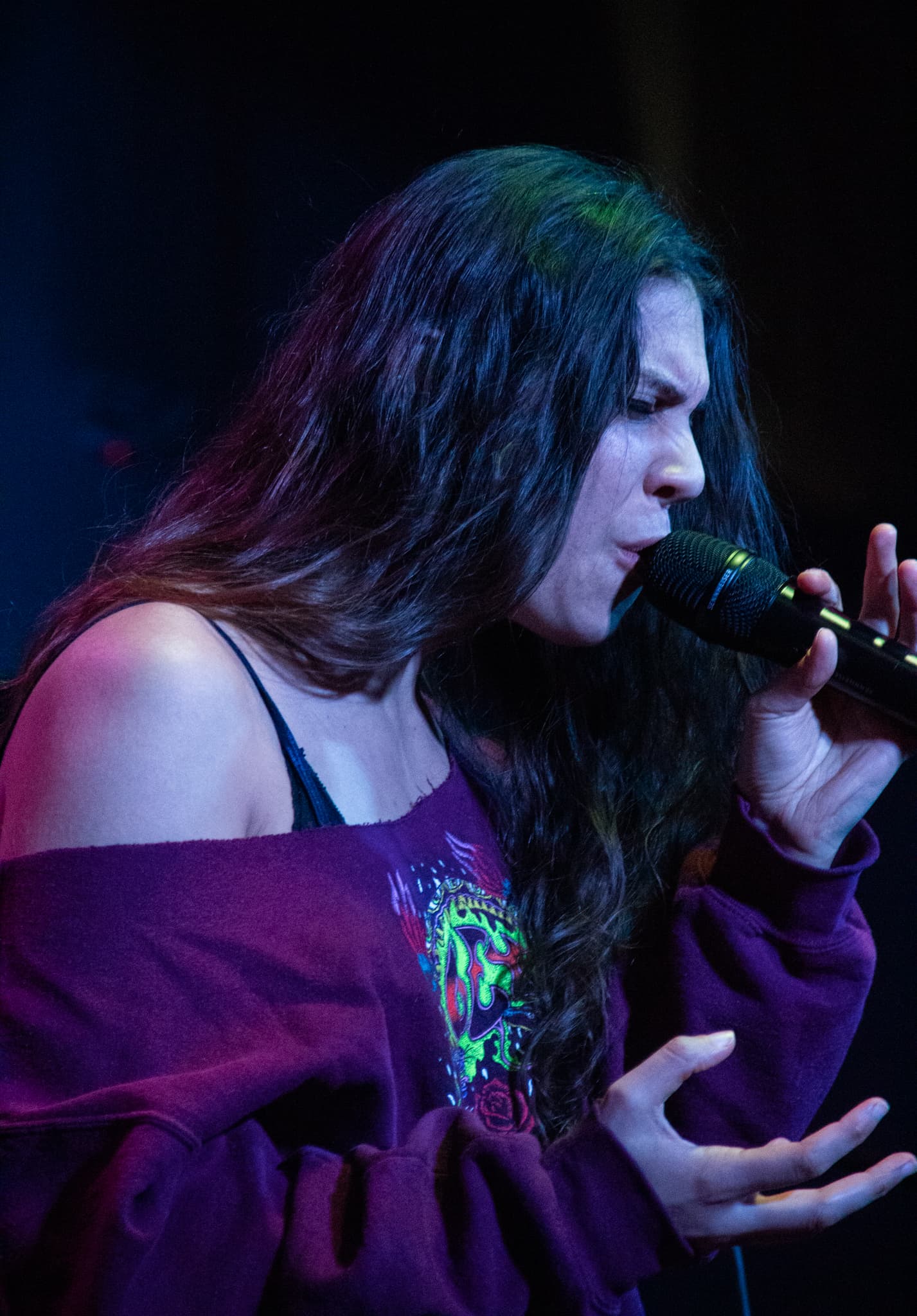 A vocalist singing under purple stage light