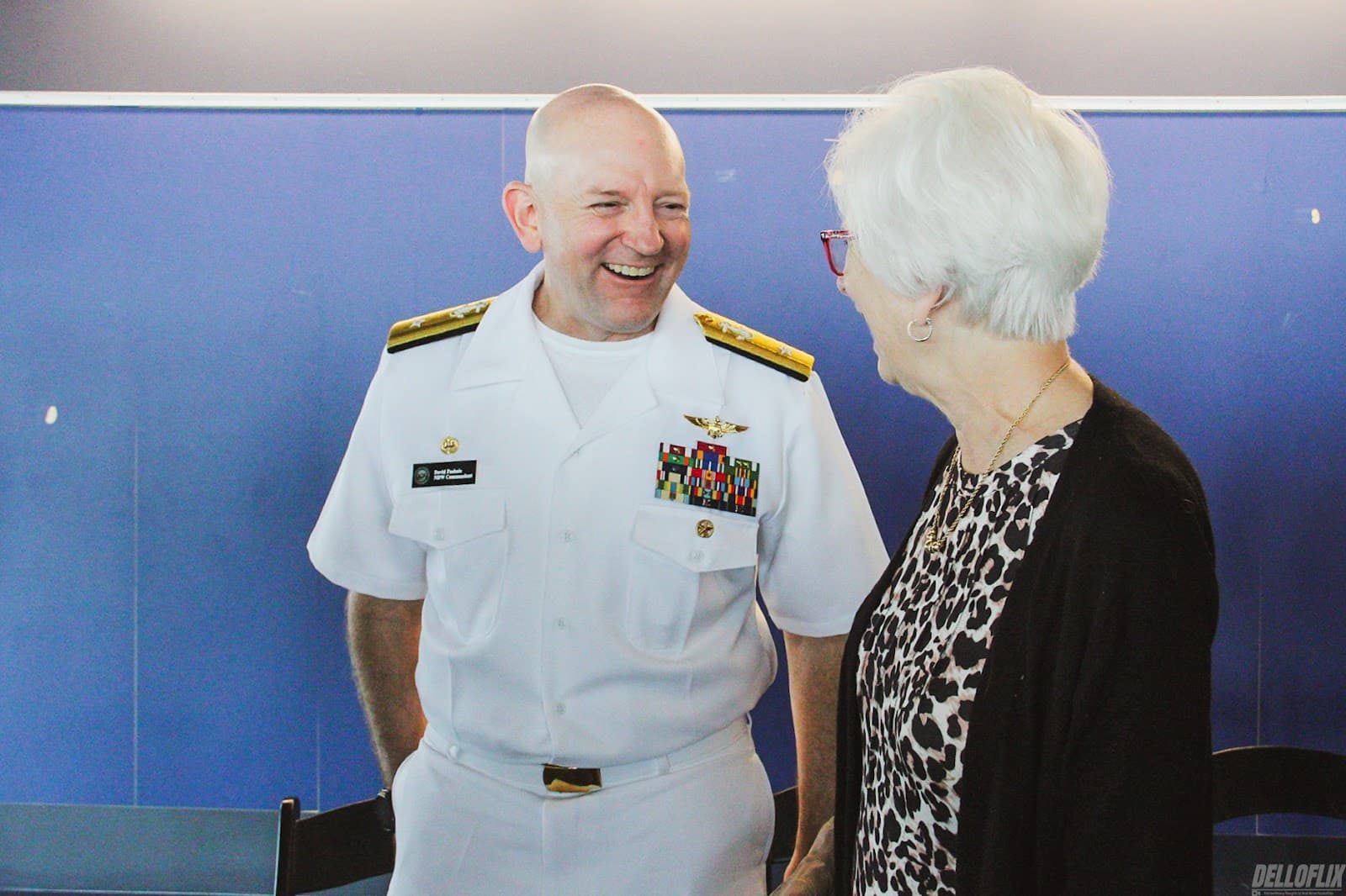 A Navy officer sharing a laugh with a guest at a reception
