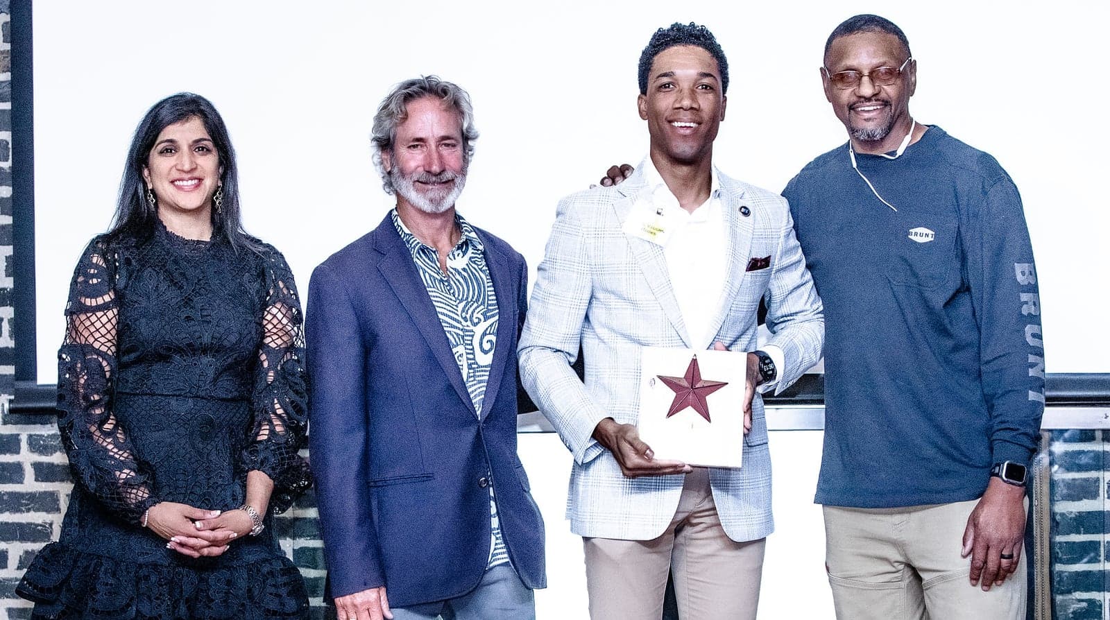 Del’Vaughn Rooks holding his 2025 Rising Star award from the Living Classrooms Foundation, standing with three fellow attendees