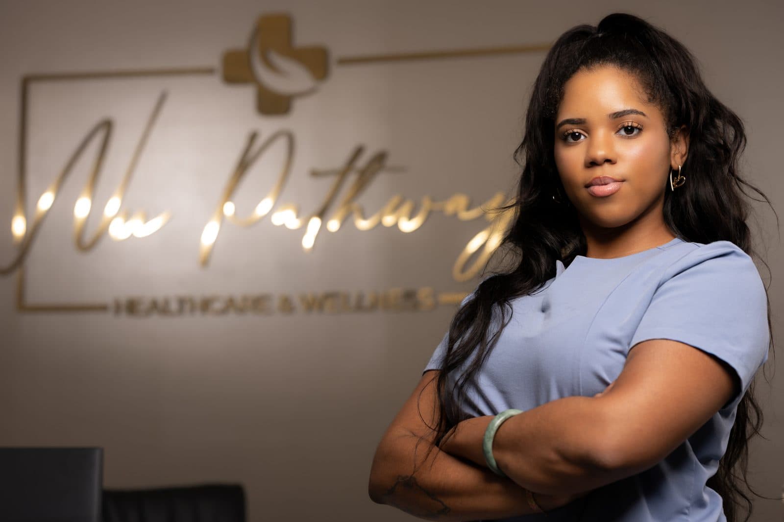 Portrait of a MedSpa team member in front of the gold logo wall