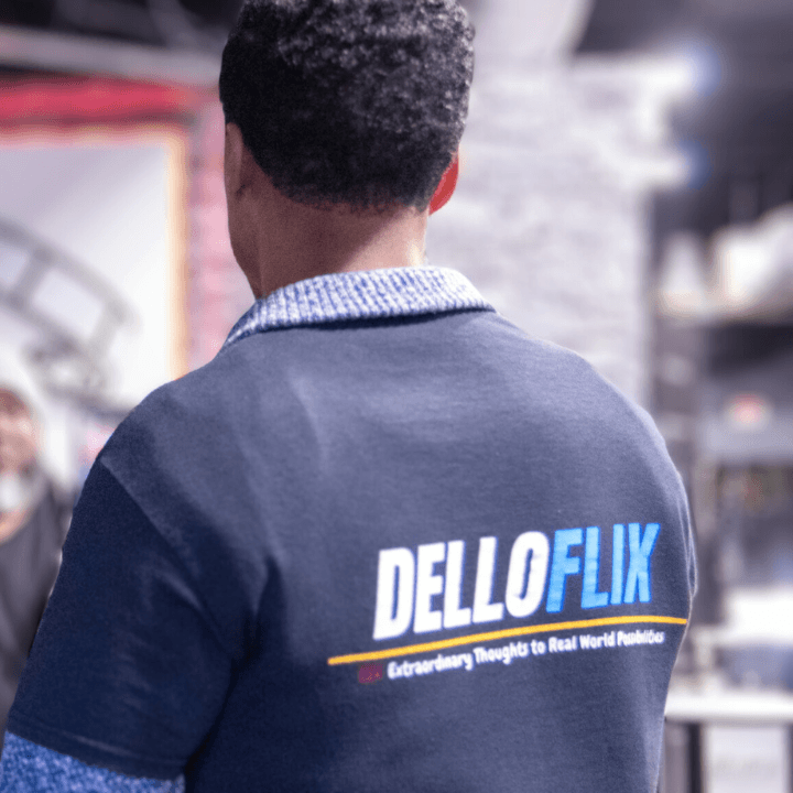 Back of a DelloFlix team member wearing a navy polo with the DelloFlix logo and tagline